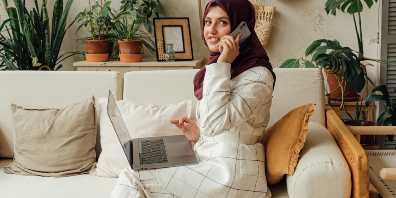 howreceiveSML An image of a lady sat on her phone and using her laptop, whilst sat on the sofa